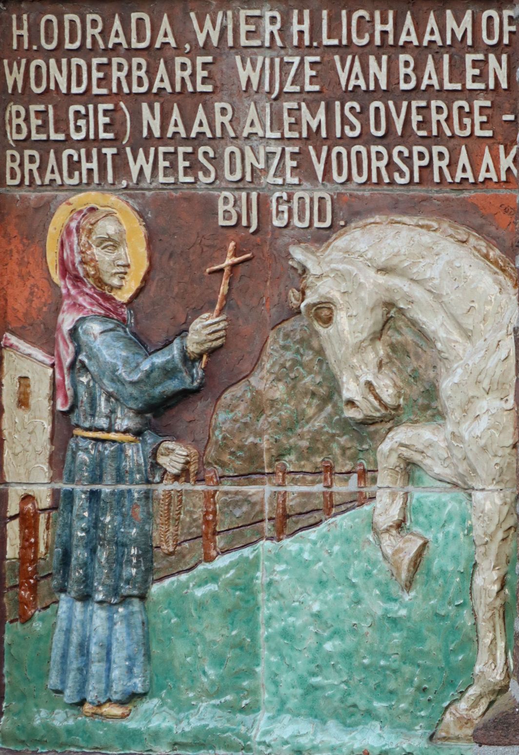 Relief: Odrada bändigt den Schimmel, ann der Kirche Sint-Hubertus in Alem